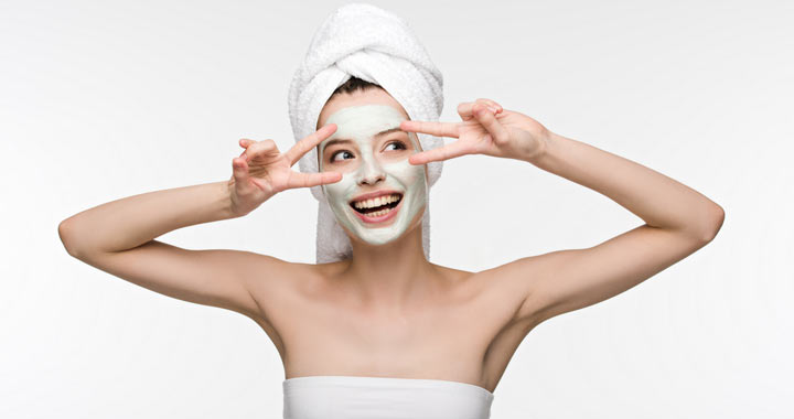 woman smiling with a facial cream mask